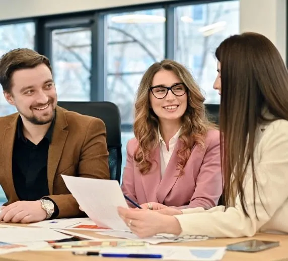 Trois collaborateurs souriants autour d’un document