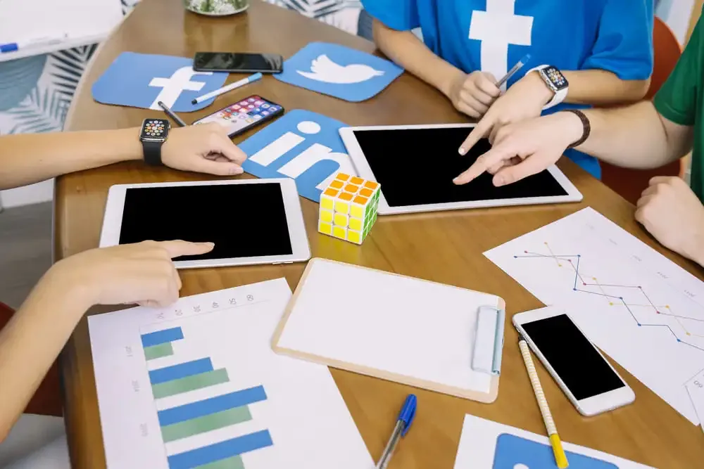 Tablettes et smartphones affichant des réseaux sociaux sur une table de travail