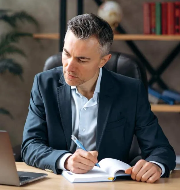 Dirigeant qui prend des notes devant son ordinateur